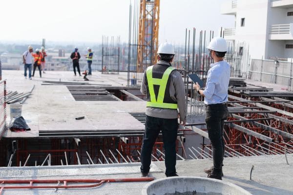 Construction engineers inspecting a high-rise building site, wearing safety gear.