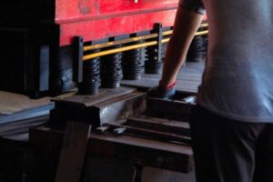 Close-up of a worker operating an industrial press machine in a factory