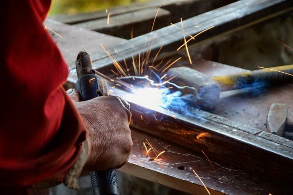 Close-up of a welder working on metal with sparks flying from the welding process.