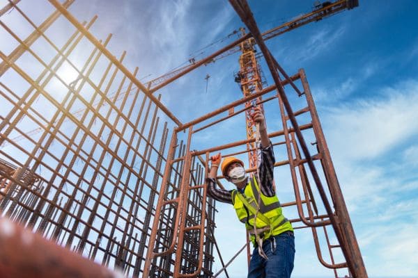 Construction worker installing steel reinforcements at a building site.