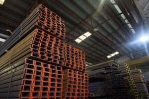 Stacks of steel I-beams inside a warehouse.