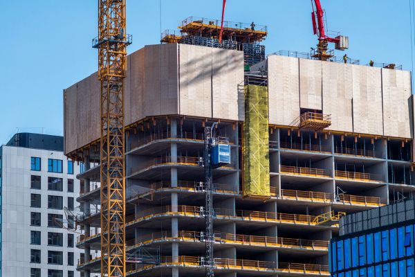 A large tubular steel building under construction, featuring a crane lifting materials into place.