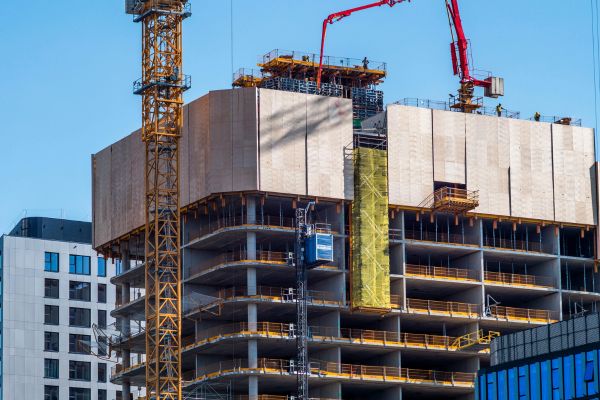 A construction crane lifts materials at a building site currently under construction.