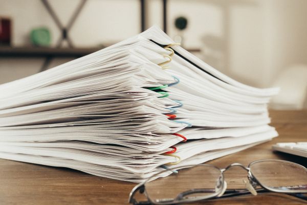 A stack of papers alongside glasses and a calculator, related to steel import documentation and calculations.