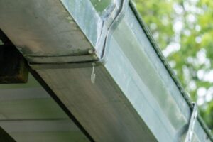 Close-up of a metal roof gutter system with water drainage detail.